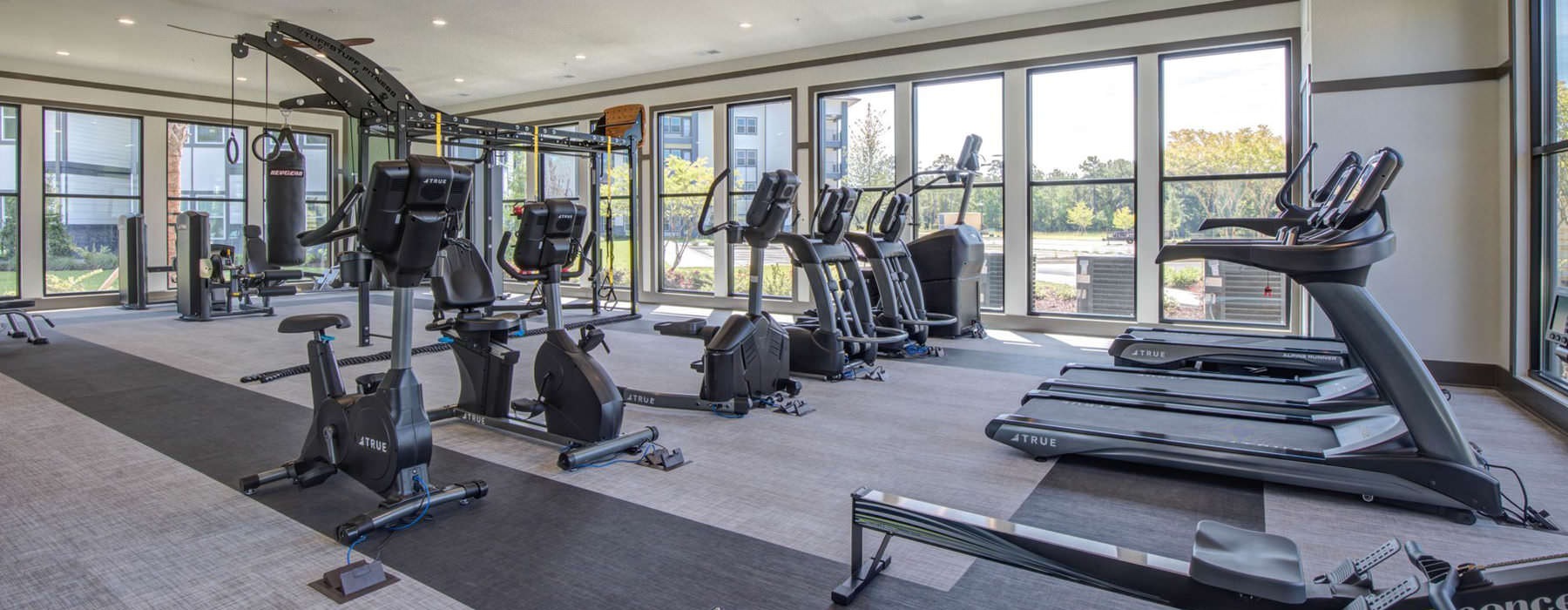 well equipped fitness center surrounded by large windows