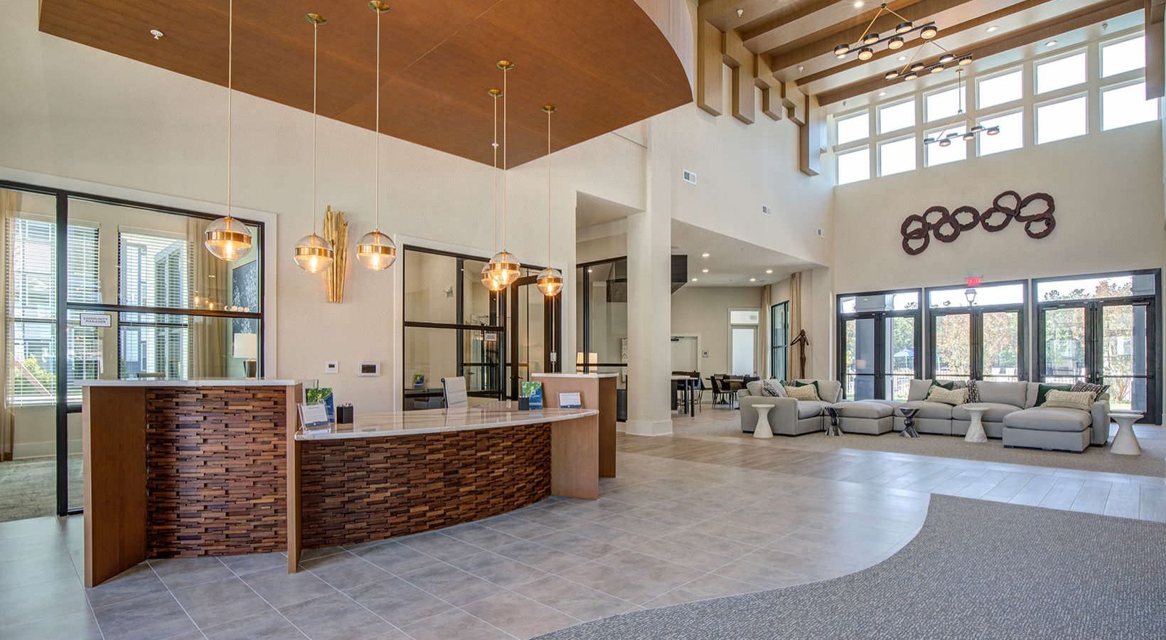 Luxurious lobby featuring a reception desk with wood accents, pendant lighting, spacious seating, and large windows.